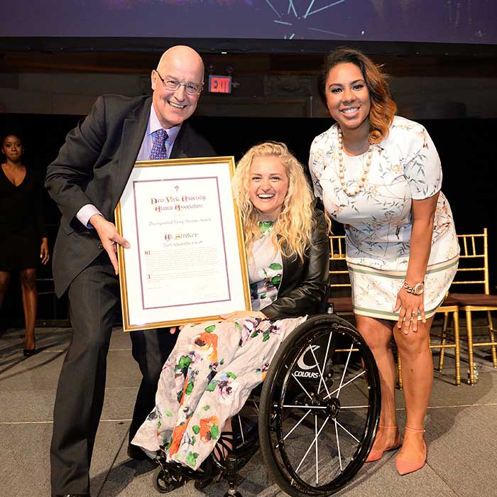 Three individuals posing with an award