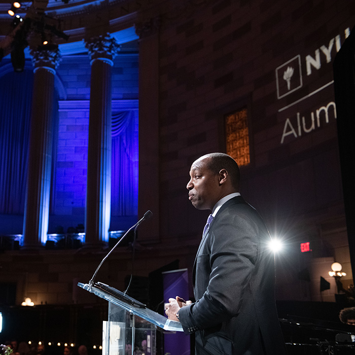 Man in suit presenting award at NYU Alumni Awards ceremony