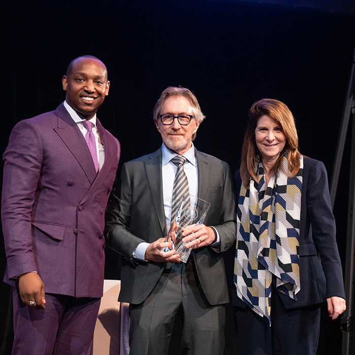Don Katz recieving award on stage from a male and female