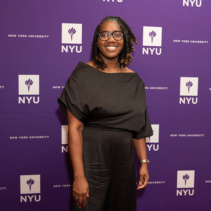 Keia Clarke standing in front of NYUAA Awards banner